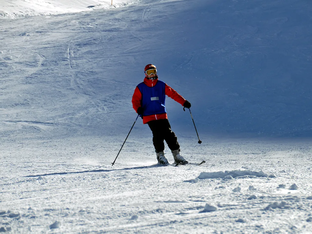 Skifahrer in roter Weste auf der Piste.
